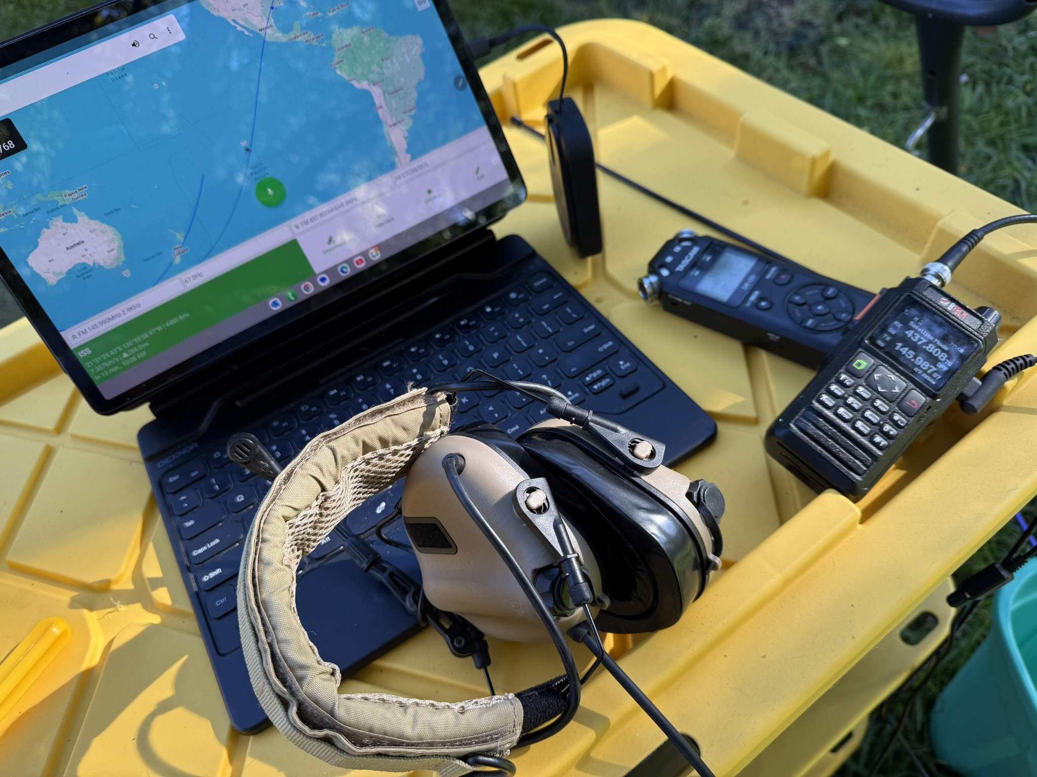 Portable ISS setup: tablet with tracker, headphones, audio recorder, and BTech UV-Pro / Vero N-76 HT on a field table